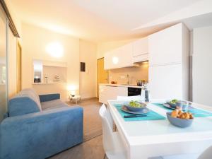 Il comprend une cuisine et un salon avec une table et un canapé bleu. dans l'établissement Parco del Mare - Relax near the sea and city centre, à Borghetto Santo Spirito 6 autres photos