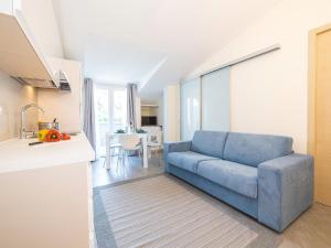 un salon avec un canapé bleu et une cuisine dans l'établissement Parco del Mare - Relax near the sea and city centre, à Borghetto Santo Spirito