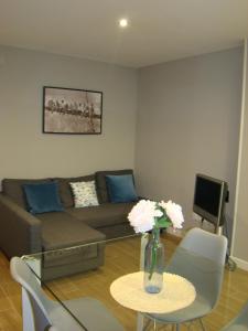 Apartamentos La Pereda Santander- Estudio E1 في سانتاندير: غرفة معيشة مع أريكة وطاولة مع زهور