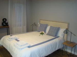 ein Bett mit weißer Bettwäsche und einer Blume darauf in der Unterkunft Apartamentos La Pereda Santander- Estudio E1 in Santander