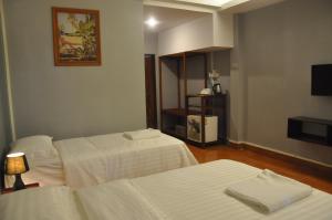a hotel room with two beds and a television at Pilgrim's Kitchen & Inn in Savannakhet