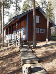 a cabin in the woods with a wooden walkway in front at Maatilamatkailu Heikin Tupa in Ylipää