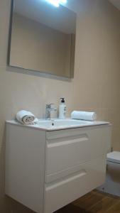 ein Badezimmer mit einem weißen Waschbecken und einem Spiegel in der Unterkunft Apartamentos LA PEREDA SANTANDER in Santander