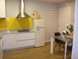 eine Küche mit einem weißen Kühlschrank und einem Tisch in der Unterkunft Apartamentos LA PEREDA SANTANDER in Santander