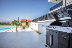 a outdoor kitchen with a stove and a swimming pool at Villa Manhattan in Dobrinj +28 photos