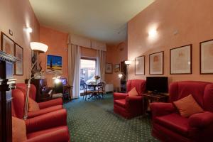 a living room with red chairs and a television at Hotel Arizona in Florence