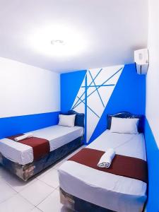 two beds in a room with blue and white at Hotel Olympic Jogyakarta by Sajiwa in Yogyakarta