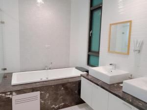 ein Badezimmer mit zwei Waschbecken, einer Badewanne und einem Spiegel in der Unterkunft 一中太陽綠墅 in Taichung