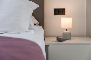 a bed with a table with a lamp on it at Apartments Marando in Dubrovnik