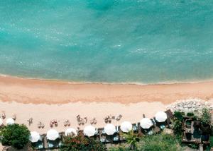 eine Gruppe von Menschen am Strand mit Sonnenschirmen in der Unterkunft Melia Bali in Nusa Dua