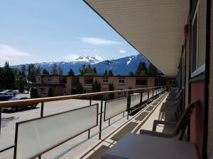 a balcony with chairs and a view of mountains at Alpine Inn & Suites in Revelstoke