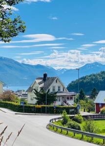 a house on a street with mountains in the background at Villa Lovise Riverside in Stranda