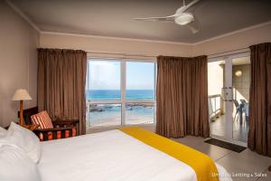 a bedroom with a bed and a large window with the ocean at Sorgente 206 in Umdloti