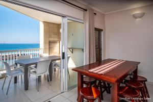 a dining room with a table and a balcony with the ocean at Sorgente 206 in Umdloti