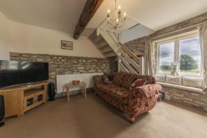 een woonkamer met een bank en een televisie bij Kirkdale Cottage in Helmsley