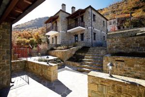 une vieille maison en pierre avec des escaliers dans une cour dans l'établissement Hotel Athina, à Elati