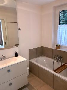a bathroom with a bath tub and a sink at Ferienhaus am Park am Röhrensee in Bayreuth