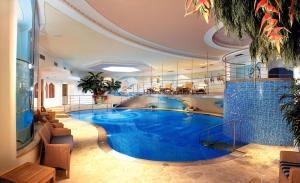 a large swimming pool in a hotel with blue water at Leading Relax Hotel Maria in Moena