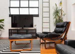 a living room with two leather chairs and a flat screen tv at StayCentral - Fitzroy Converted Warehouse Penthouse in Melbourne