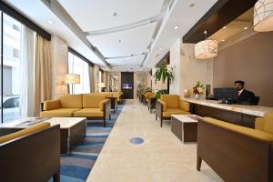un vestíbulo con sillas amarillas y un hombre sentado en un escritorio en Harbour Suites Hotel en Manama