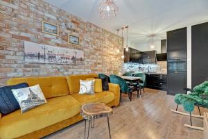 a living room with a yellow couch and a brick wall at GRANO APARTMENTS Gdańsk Old Town SPA & Wellness in Gdańsk