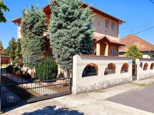 a white fence in front of a house with trees at Airport Luxury Apartman 42 in Vecsés