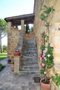un escalier en pierre menant à un bâtiment fleuri dans l'établissement Agriturismo Il Casalino, à Pienza