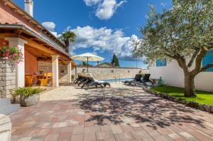 een patio met stoelen, een boom en een zwembad bij Casa Bepi in Kanfanar