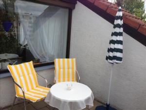 two chairs and a table and an umbrella on a patio at Ferienwohnung Mühlbach in Isny im Allgäu