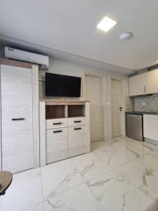 a large kitchen with white cabinets and a flat screen tv at Apartments Nera Paralia-Apartment with sea view in Paralia Katerinis