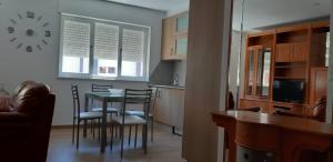 a kitchen with a table and chairs and a clock on the wall at Apartamento Laura in O Pindo
