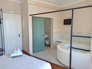 a bathroom with a tub and a bed and a tub and a toilet at Hotel Amphora in Chania Town