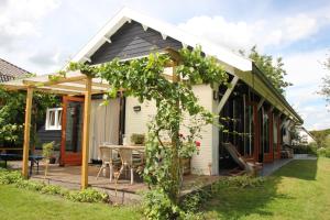 uma casa com uma pérgola e uma mesa em Familiehuis De Betuwe met prive kunstgras tennisbaan en sauna em Erichem