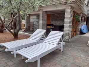 2 chaises longues blanches assises sur une terrasse dans l'établissement Apartments Tonka Grebaštica, à Grebaštica