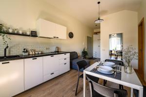 a kitchen with white cabinets and a table with chairs at Modern studio - 10min walk to the sea in Liepāja