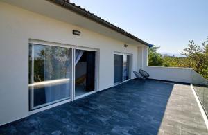a balcony with glass doors and a chair on it at Apartman Izzy in Senj