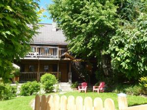 une maison avec deux chaises rouges devant elle dans l'établissement "CHALET LES ARAVIS" chalet et Appartements, au Grand-Bornand