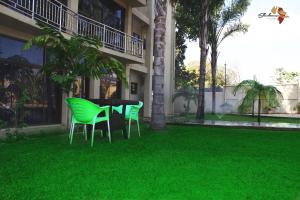 two green chairs and a table in front of a building at Sherbourne Hotel in Kitwe