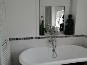 Baño blanco con lavabo y espejo en Chambre Le Notre Le Domaine Des Jardins De Bracquetuit, en Bracquetuit