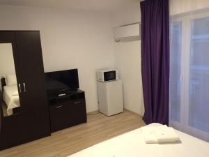 a bedroom with a bed and a tv and a window at Beach House in Mamaia Sat/Năvodari