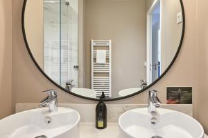 La salle de bains est pourvue de 2 lavabos et d'un grand miroir. dans l'établissement Aparthotel & Spa Adagio Vannes, à Vannes