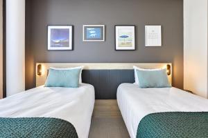 two beds in a hotel room with blue pillows at Aparthotel & Spa Adagio Vannes in Vannes