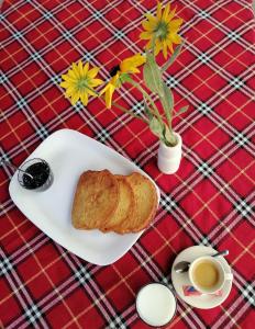 a plate of bread and a cup of coffee and flowers at Семеен Хотел "При Мечо" in Rilski Manastir