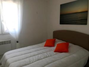 a bed with two red pillows on top of it at À moins de 100 mètres de la mer a la pointe de Trevignon in Trégunc