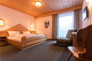 a bedroom with a bed and a chair and a window at Hotel Hafele in Kaunertal