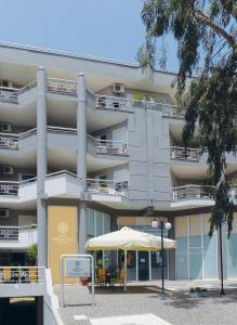 un gran edificio con una sombrilla delante de él en Hotel Arethousa, en Loutra Edipsou