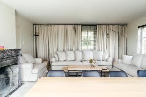 a living room with white furniture and a fireplace at Hoeve Hazegras in Knokke-Heist