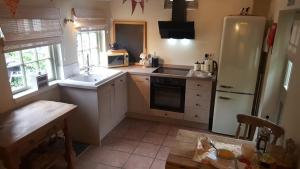 a kitchen with a white refrigerator and a sink at Dairy Cottage Luxury B&B in Attleborough