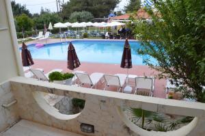 a view of a swimming pool with chairs and umbrellas at Nikos Apartments in Stalida