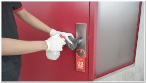 a person in gloves unlocking a door with a cleaning glove at RedDoorz near XT Square Yogyakarta in Yogyakarta